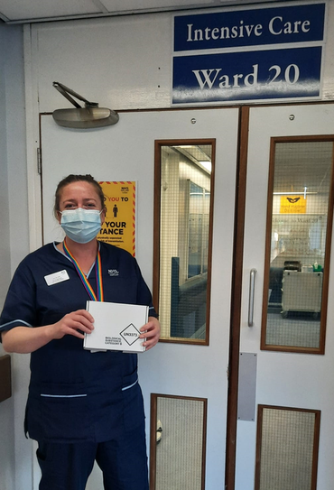 Photo of a Research Nurse holding a sample kit box outside intensive care Ward 20